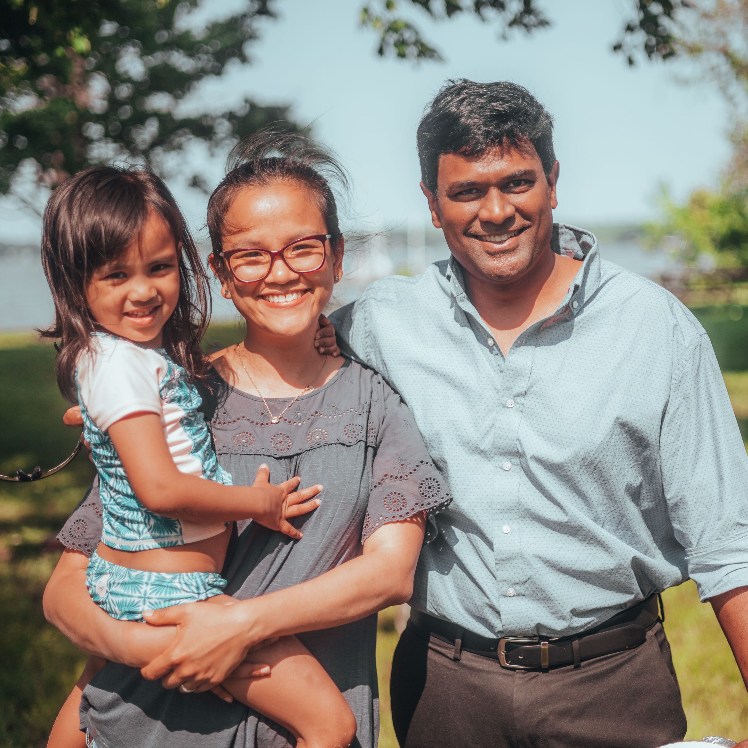 Smiling family enjoying time together outdoors in a sunny summer setting.